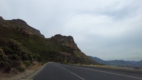 Carretera-Pavimentada-A-Lo-Largo-De-La-Costa-Con-Montañas-Rocosas,-Ciudad-Del-Cabo,-Sudáfrica