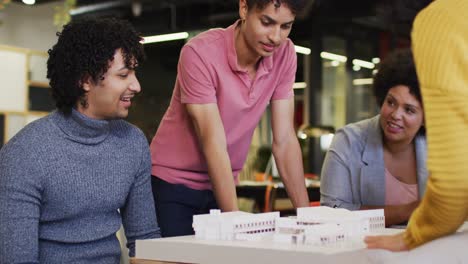 Happy-diverse-business-people-discussing-work-with-model-at-office