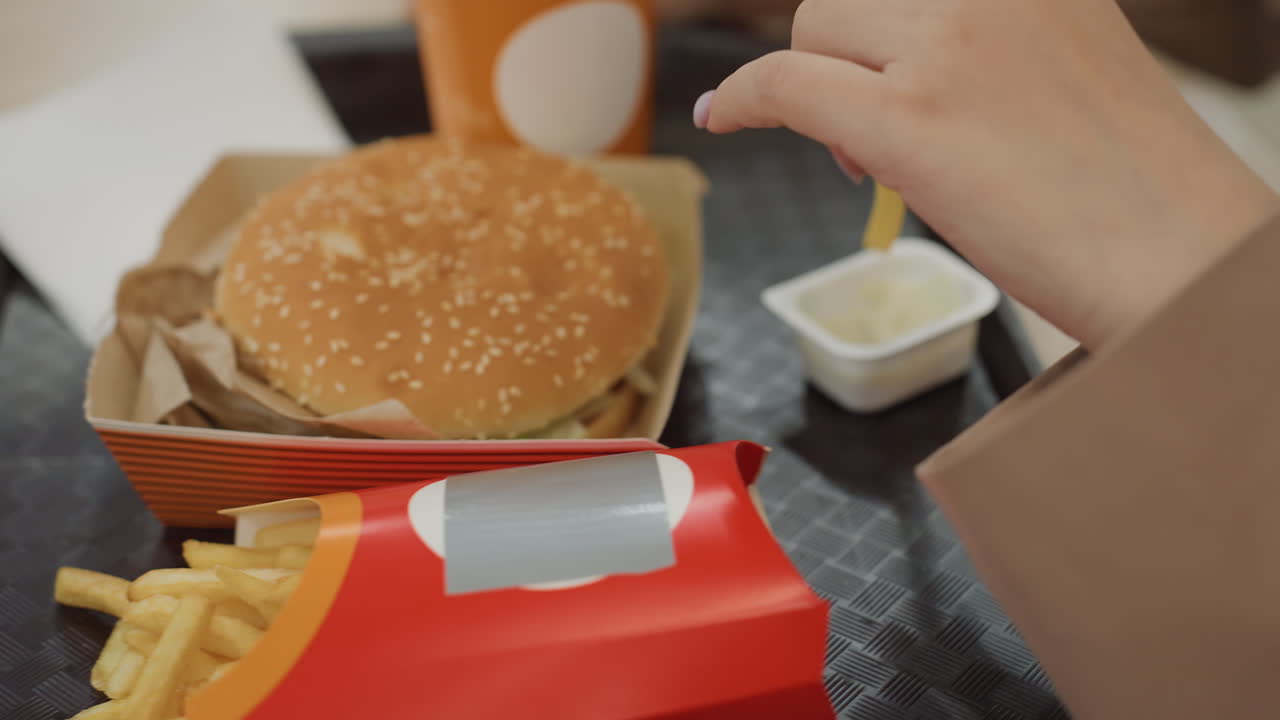 양념이 준비된 편안한 식사, 식사 준비가 한창인 활기 넘치는 푸드홀 풍경, 식사를 즐기기 전에 냅킨과 소스를 정리하는 사람을 보여주는 활기찬 푸드 코트 환경