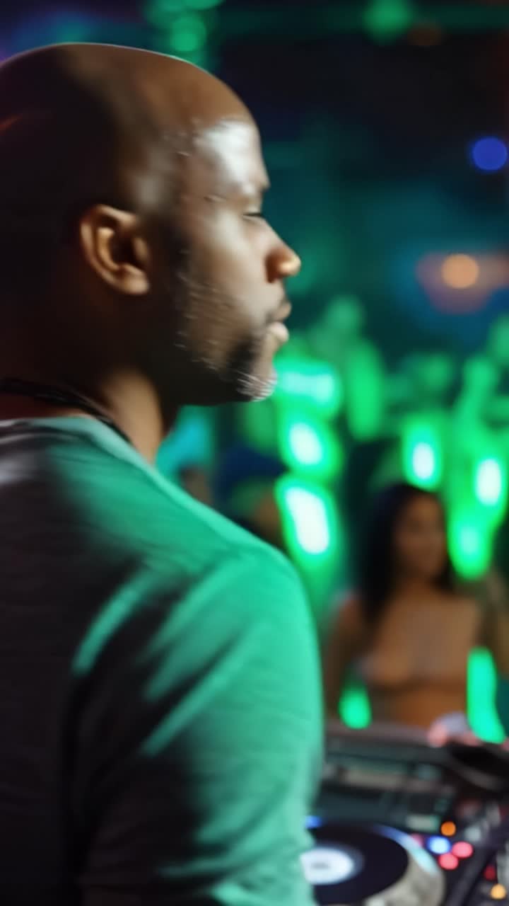 Bareheaded man stands with back to camera. Green lights pulse behind him, creating vibrant glow. He's focused, calm, immersed in music control. Ideal for nightclub, party, or DJ scene visuals