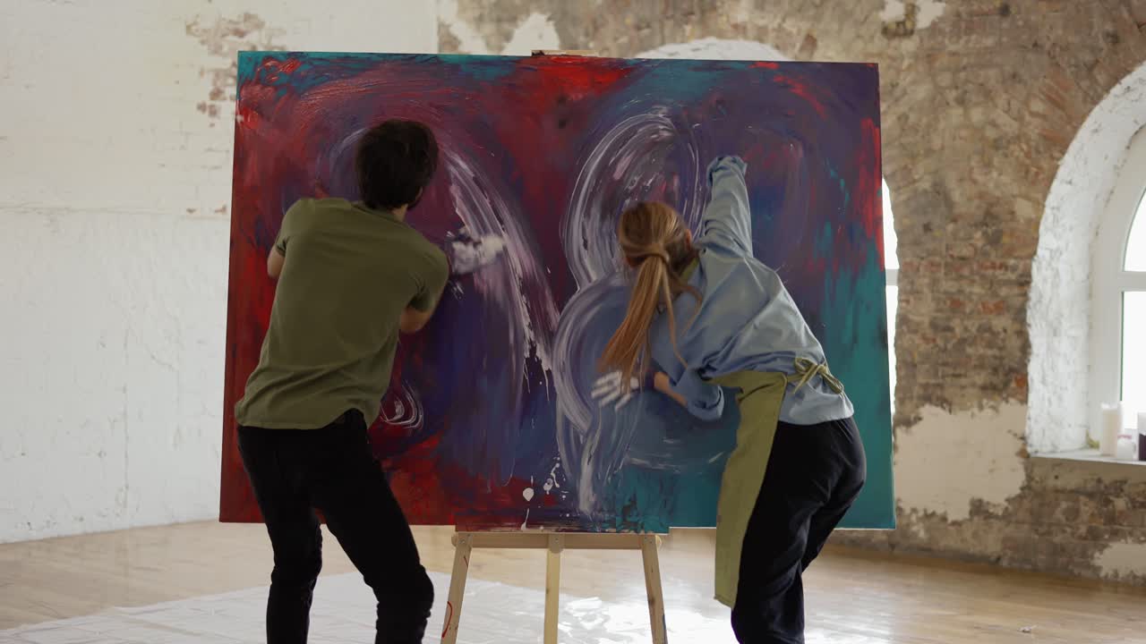 열정적인 커플이 캔버스에 다채로운 페인트를 묻히고 함께 그림을 만 ⁇ 니다.
