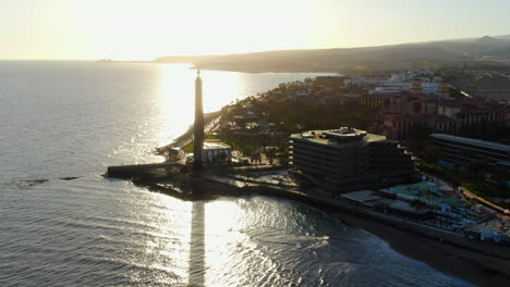 Hermosa-Toma-Aérea-En-órbita-Durante-La-Puesta-De-Sol-Del-Faro-De-Maspalomas,-Con-Hermosos-Colores-De-La-Tarde