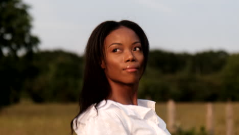 mujer negra caminando en el campo mientras mira el atardecer durante un cálido día soleado