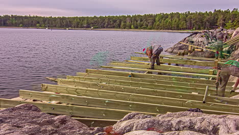 hombres trabajadores construyendo un marco de madera en la costa rocosa del lago, lapso de tiempo de fusión