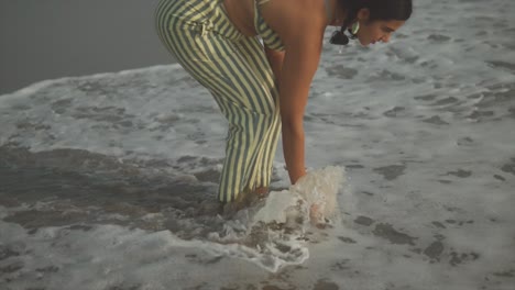 vista de cerca de una hermosa mujer juega en las olas de agua salada mojando sus pies en india