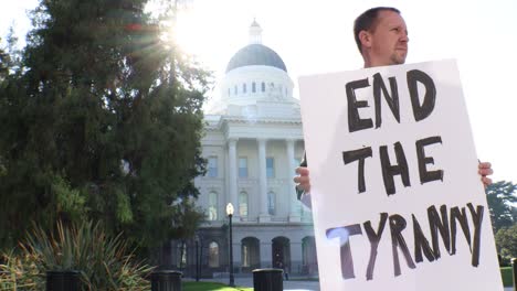 male political protester with end the tyranny sign slider dolly tracking shot