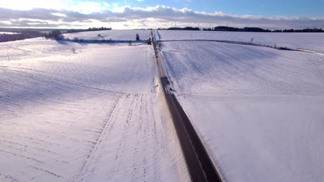 Un-Automóvil-En-Movimiento-En-Una-Carretera-Que-Conduce-Cuesta-Arriba-Y-Hacia-El-Horizonte-Con-Turbinas-Eólicas