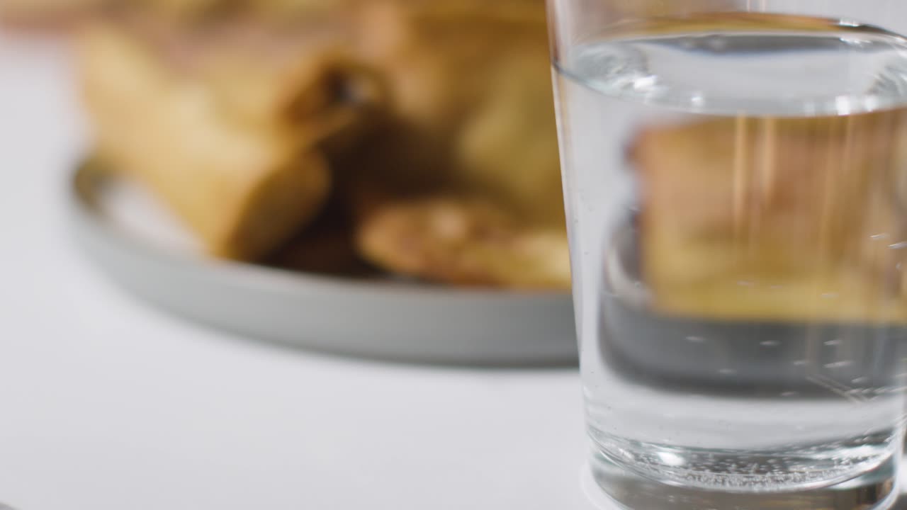 primer plano de un plato de samosas y un vaso de agua sobre una superficie de mármol celebrando el festival musulmán del eid 1