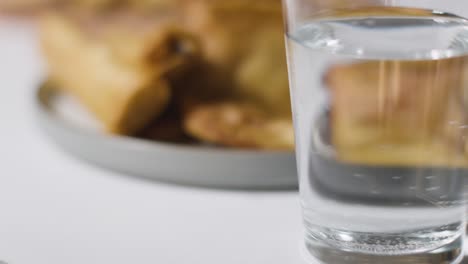 Close-Up-Of-Plate-Of-Samosas-And-Glass-Of-Water-On-Marble-Surface-Celebrating-Muslim-Festival-Of-Eid-1