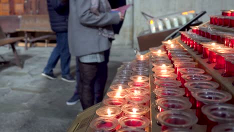 people lighting candles on the machines inside a cathedral, wishes and prayers to the saints represented