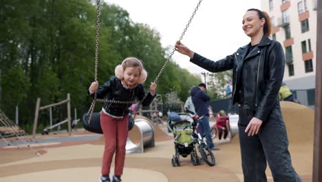 madre e hijos jugando en el columpio en el parque