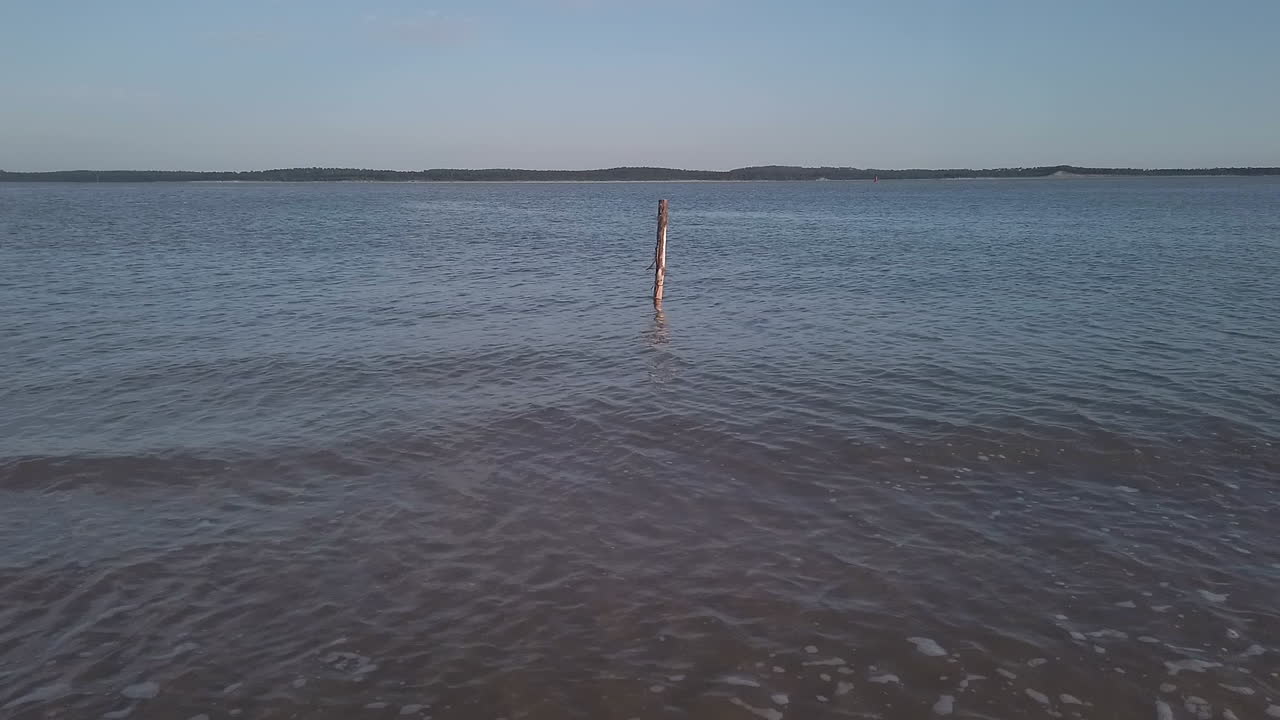 pequeñas olas en una playa francesa con una estaca de madera en el agua, charente marítimo, oléron, francia
