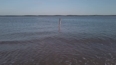 Pequeñas-Olas-En-Una-Playa-Francesa-Con-Una-Estaca-De-Madera-En-El-Agua,-Charente-Marítimo,-Oléron,-Francia