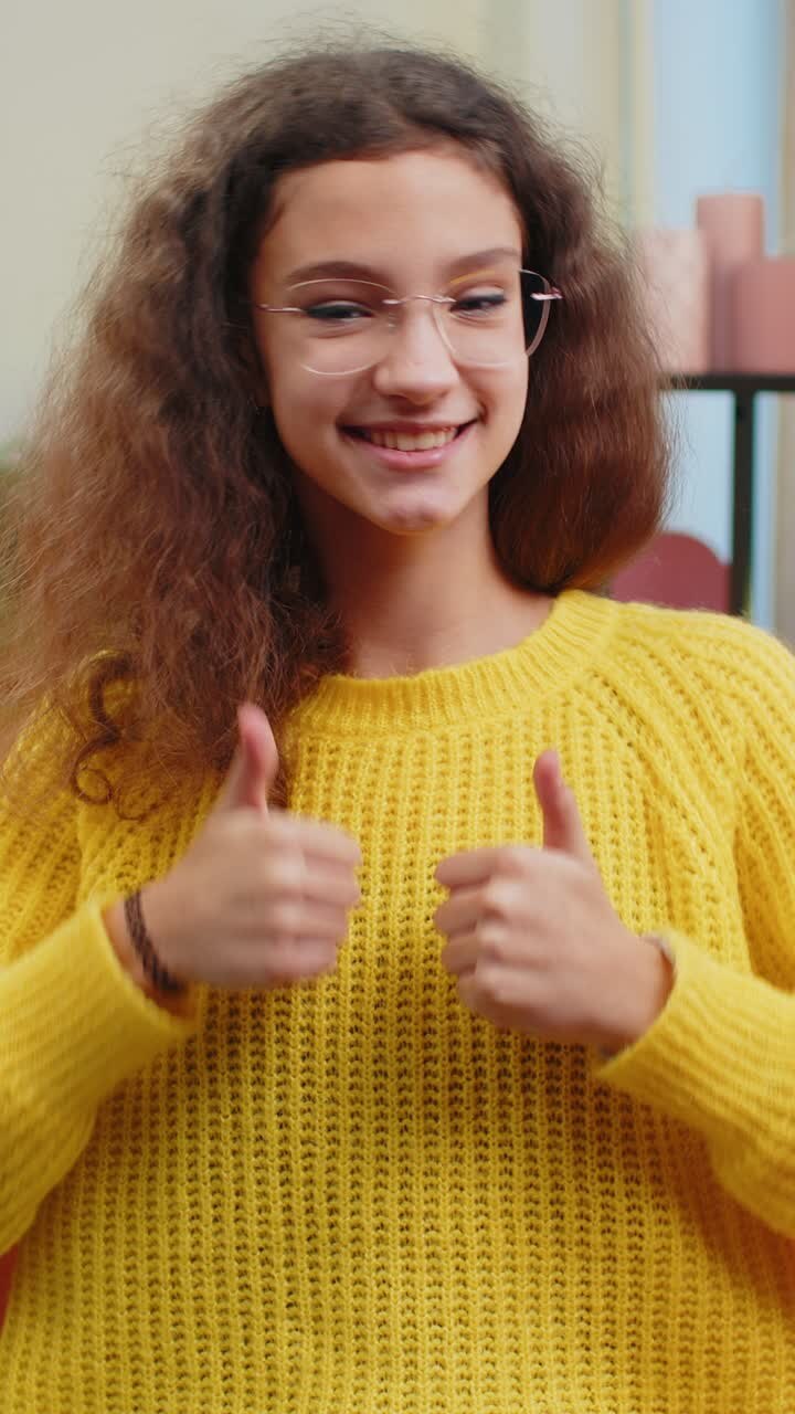 Bambina felice bambina che guarda con approvazione la telecamera mostrando i pollici in alto come un segno positivo buone notizie