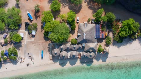 Aerial-top-down-rising-over-thatched-roofs-of-huts-at-Cueva-de-los-Pescadores,-Pedernales