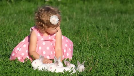 little girl playing with bunnies in the grass