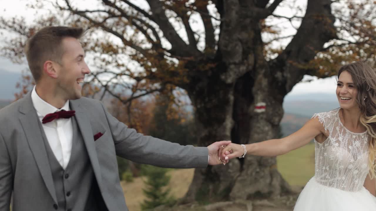 Dağ yamacında el ele yürüyen sevimli genç yeni evli gelin ve damat, evli çift.