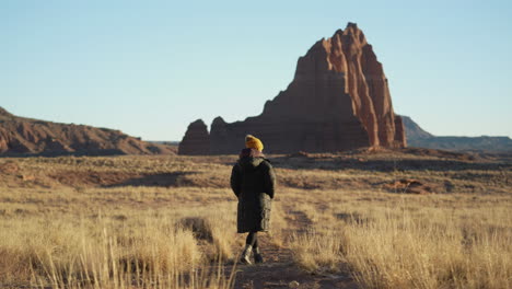 vista posterior de una mujer con ropa cálida caminando por un camino en el parque nacional capitol reef, utah, ee.uu.