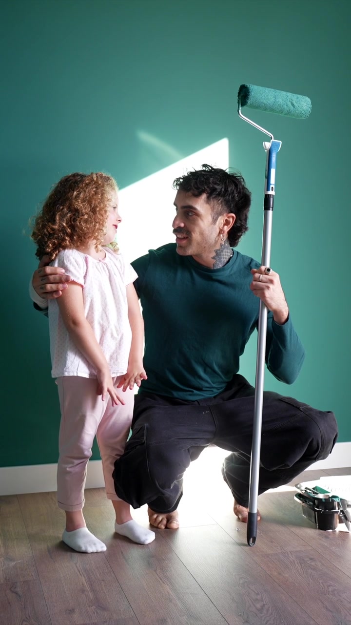 Father and Daughter Talking While Painting a Wall at Home