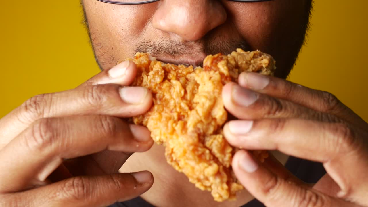 Person Eating a Piece of Fried Chicken