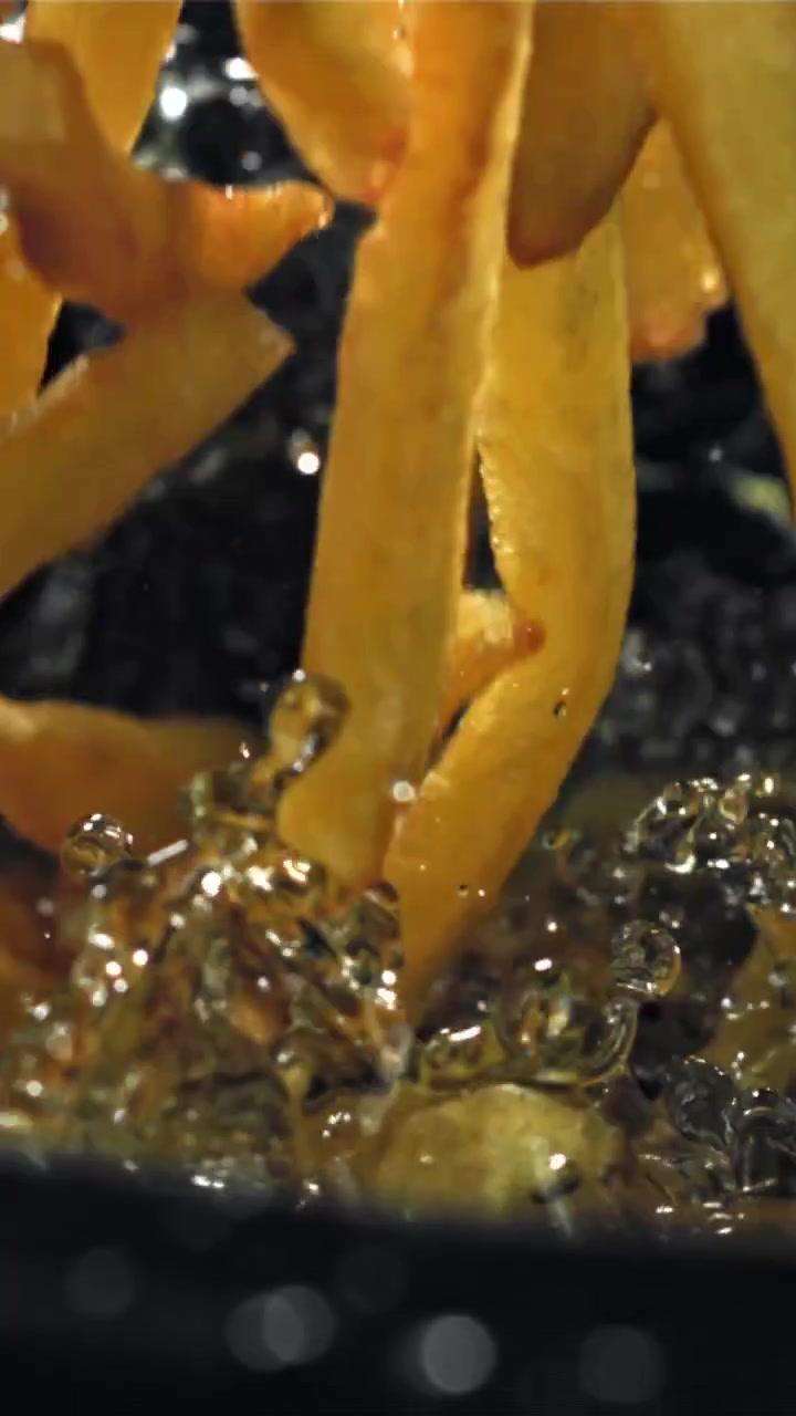 Patatine fritte croccanti che cadono nell'olio bollente e ribollente
