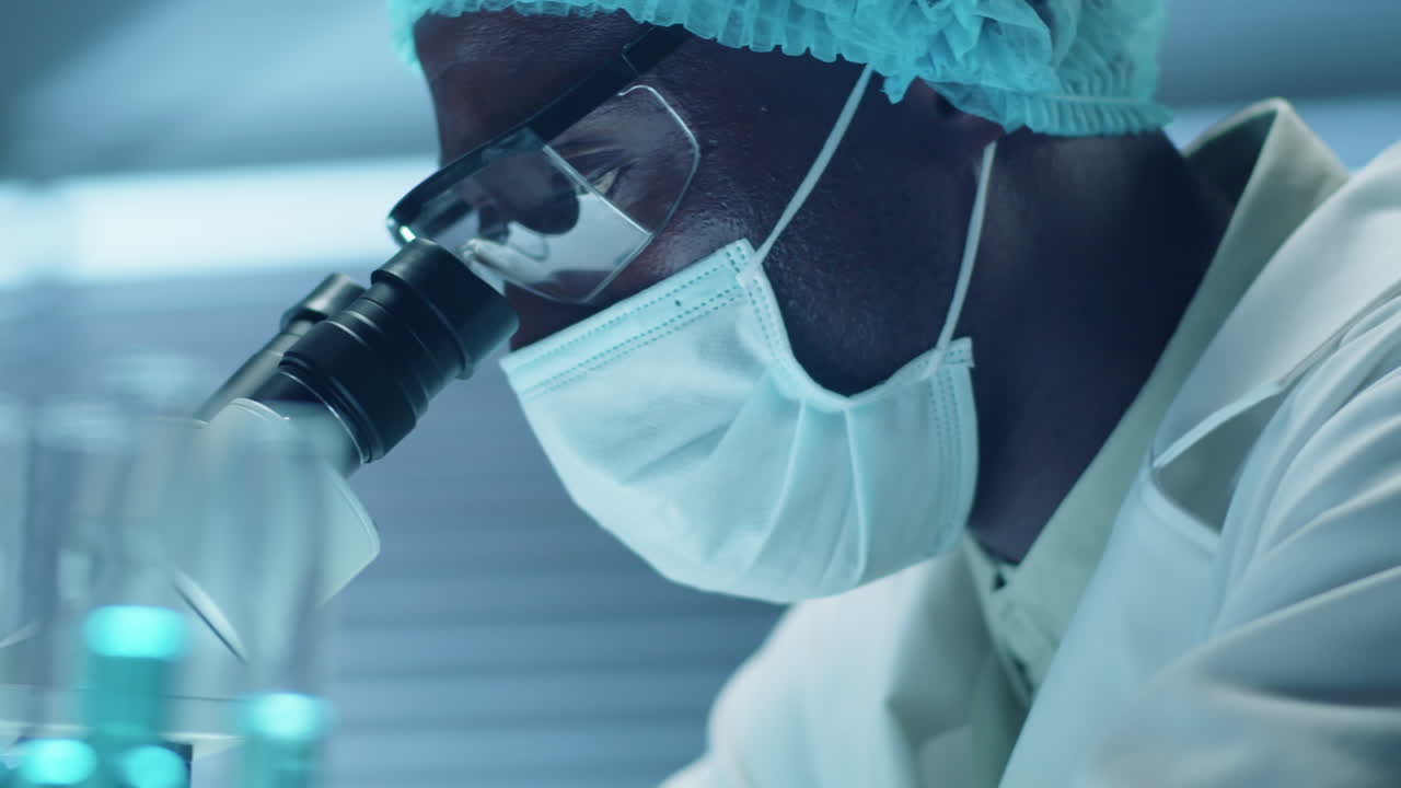 Masked Scientist Using Microscope in Laboratory