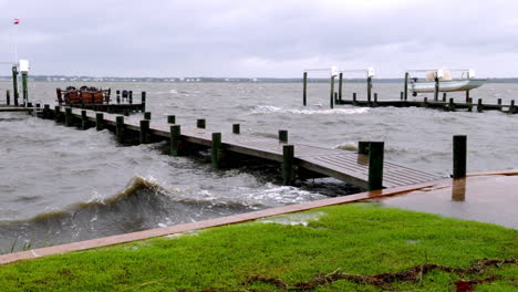 las olas salpican sobre un muelle de una oleada de tormenta de huracán, tiro amplio