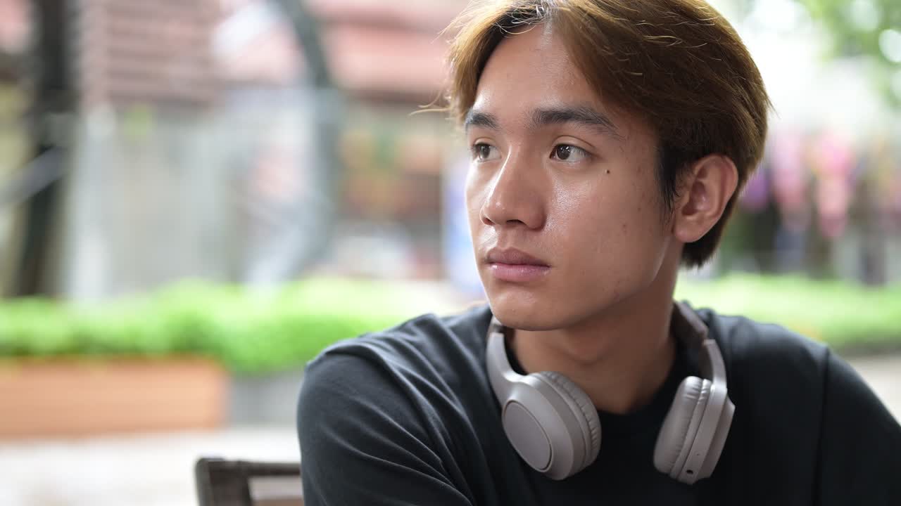 Portrait of a young Thai Asian man smiling in casual style thinking then looking at camera and smiling. Confident, relaxed, and authentic look suitable for various concepts and uses