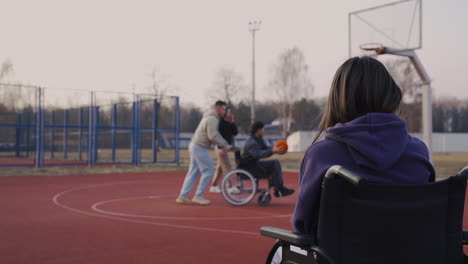 Behinderte-Frau-Im-Rollstuhl-Nimmt-Mit-Smartphone-Zu-Ihren-Freunden-Auf,-Die-Basketball-Spielen