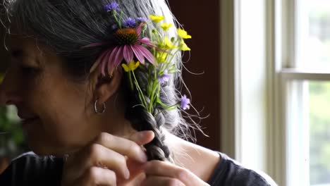 a woman adorning her hair with wildflowers, celebrating nature's beauty and creativity, capturing the elegance of floral arrangements in a serene setting