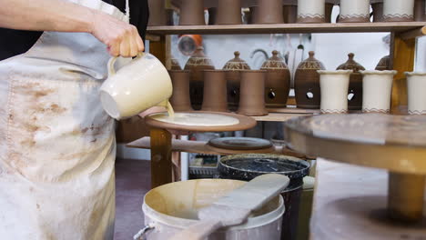 close up of male potter pouring glaze onto clay plaque for house sign in ceramics studio