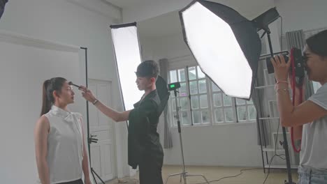 artista de maquillaje aplicando maquillaje a un modelo en el estudio