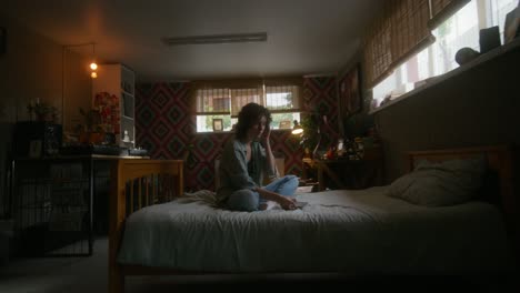 mujer joven en el dormitorio usando el teléfono