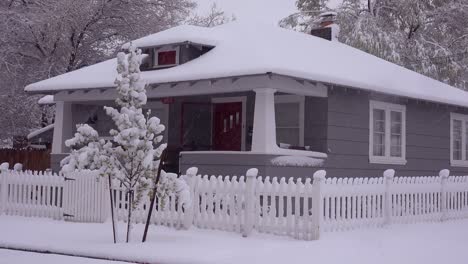 una pequeña casa está cubierta de nieve durante una tormenta de nieve