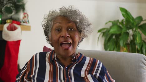 happy african american senior woman gesturing, having video call at christmas time