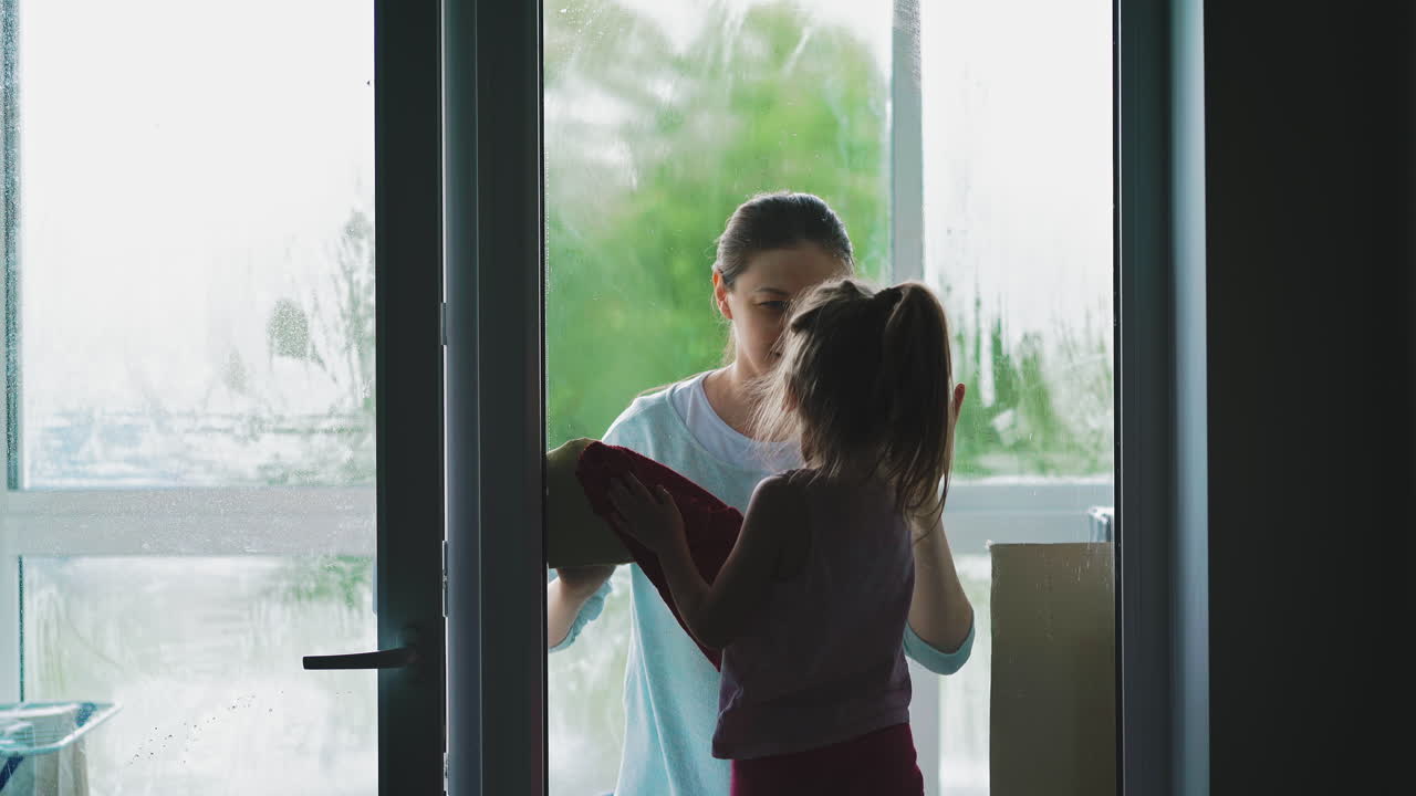 딸과 어머니는 방에서 부드러운 옷으로 깨 ⁇ 한 유리 문을