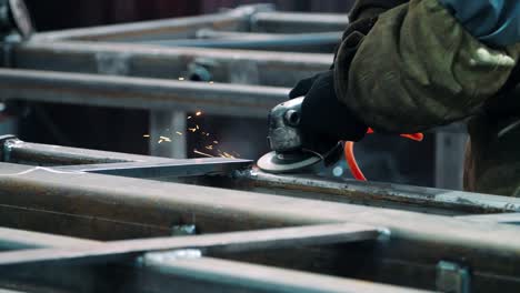 man in work gloves polishing surface of metallic unit with angle grinder