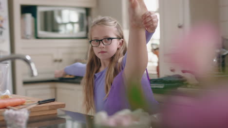 happy ballerina girl dancing in kitchen having fun practicing ballet dance moves wearing purple tutu at home