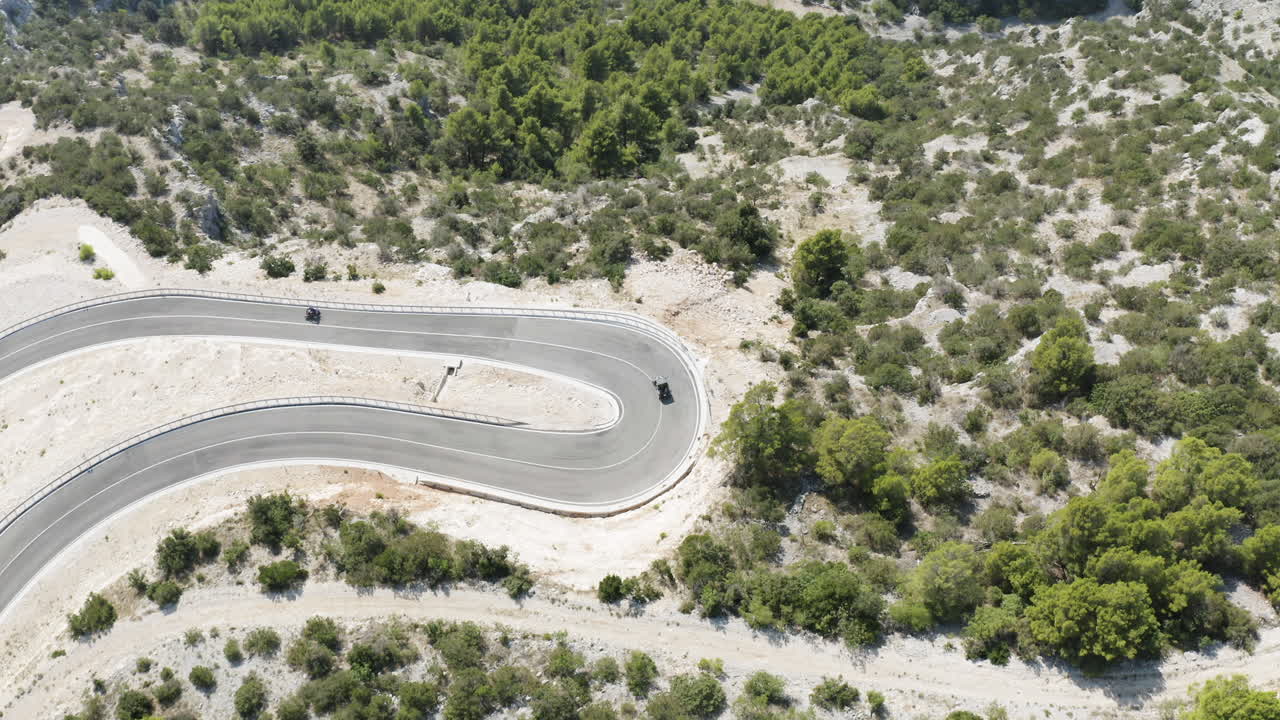 Vista aérea superior de buggies de praia virando em uma estrada sinuosa na Ilha de Brač, Croácia.