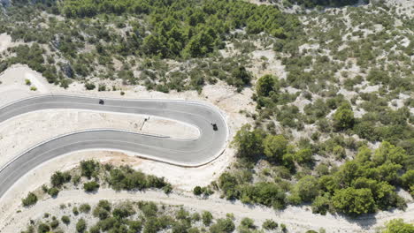 top aerial view of beach buggies turning sharp hairpin road on brac island, croatia