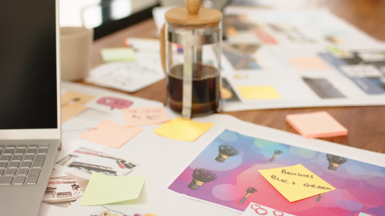 Al principio, la cámara se desplaza sobre el escritorio mostrando materiales de diseño y café, lo que permite apreciar el espacio de trabajo