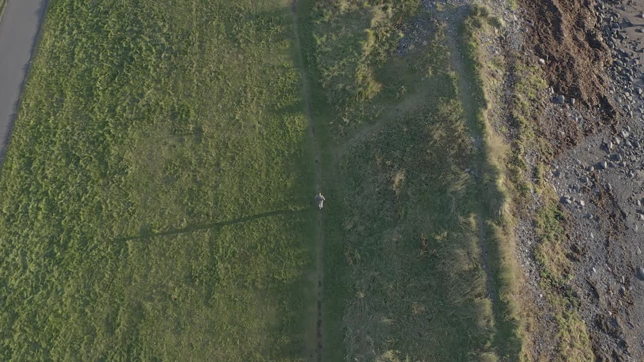 황금 시간 동안 아이슬란드 해안의 잔디 길을 달리는 남성 조깅하는 사람, 공중