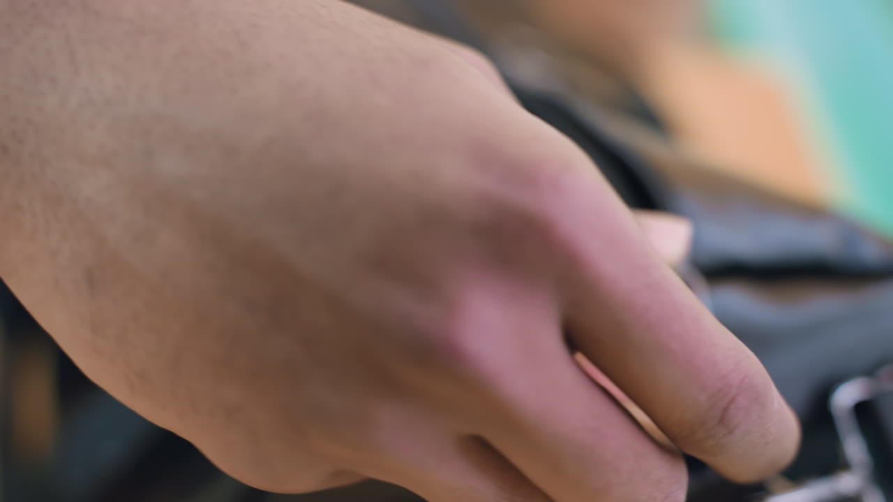 Close up hand view of person unzipping black bag indoors, showing detailed action of preparation and focus on equipment handling with soft blurred background