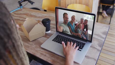 mujer tomando un bocadillo mientras hace una videollamada en una computadora portátil en una cafetería