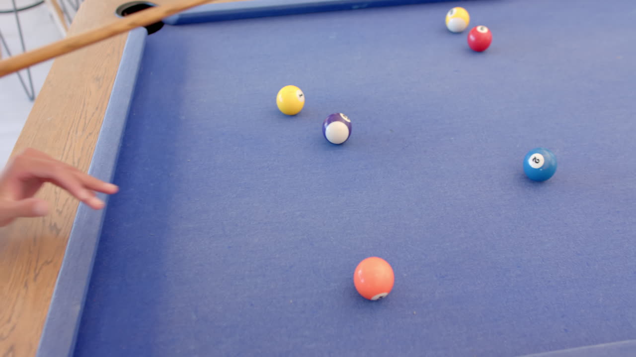 Playing billiards, person aiming cue stick at balls on pool table
