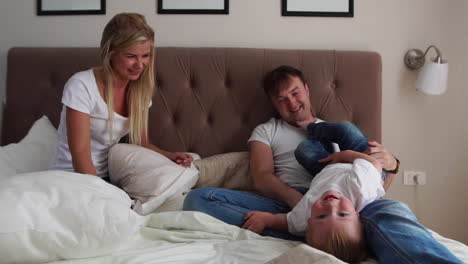 happy family playing to pillows fight on bed at home