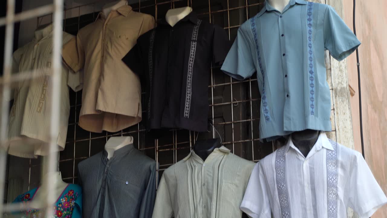 la cámara muestra una variedad de camisas de guayabera para hombres de vendedores ambulantes en mérida, méxico.