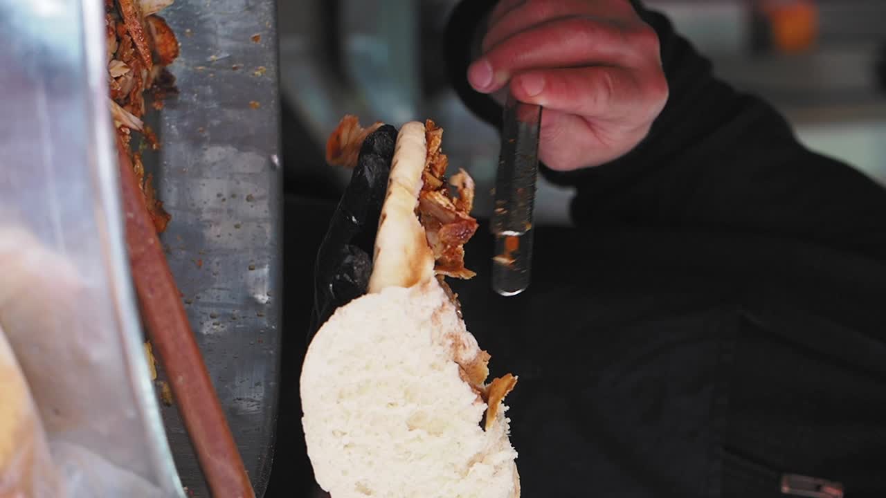 Primo piano di mani che preparano un panino döner kebab