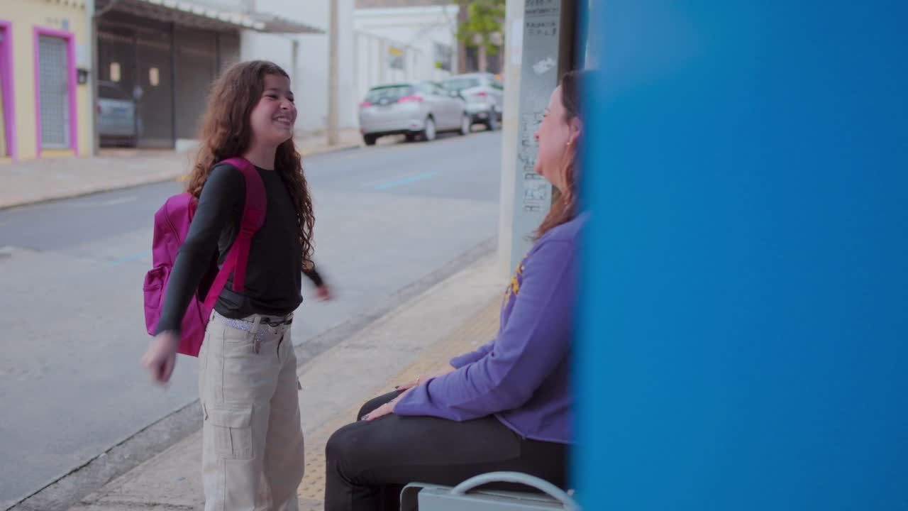 Happy Mother and Daughter Interacting at a Bus Stop