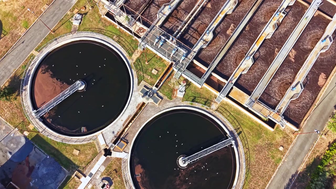 Water treatment facility overview with circular tanks and processing equipment in a city environment